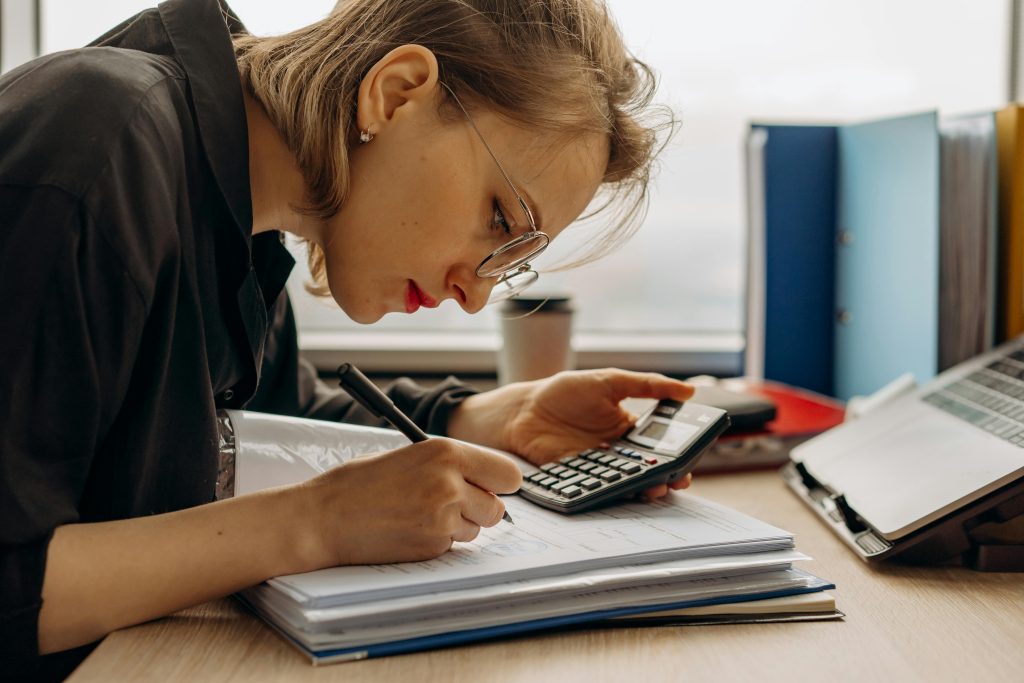 Person calculating and taking notes. Blockchain Proof Against AI Forgery in finance and accounting.
